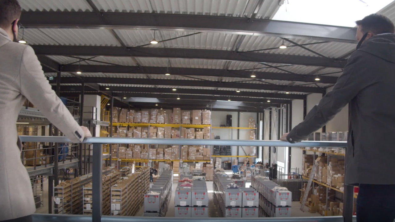 Marcel (l) en Bas (r) kijken vanaf de vide uit op het pas verhuisde magazijn in het nieuwe pand.