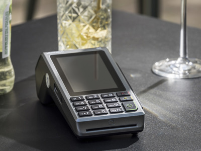 Pinautomaat met druktoetsen op een tafel in een horecazaak, naast glazen